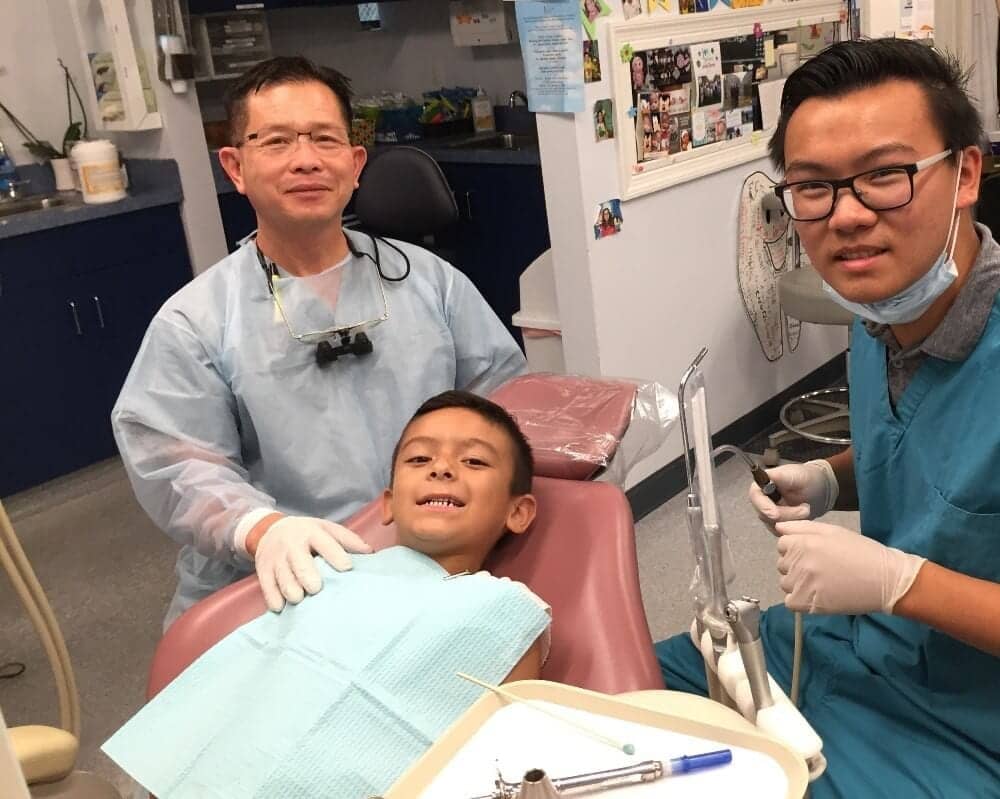 Photo of Dr. Thein and his nephew volunteering at the Kids' Community Dental Clinic